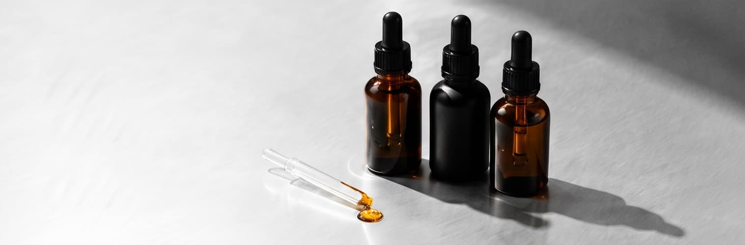 Three dropper bottles and a pipette on a white bench