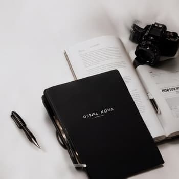 A notebook, pen and camera on an open magazine